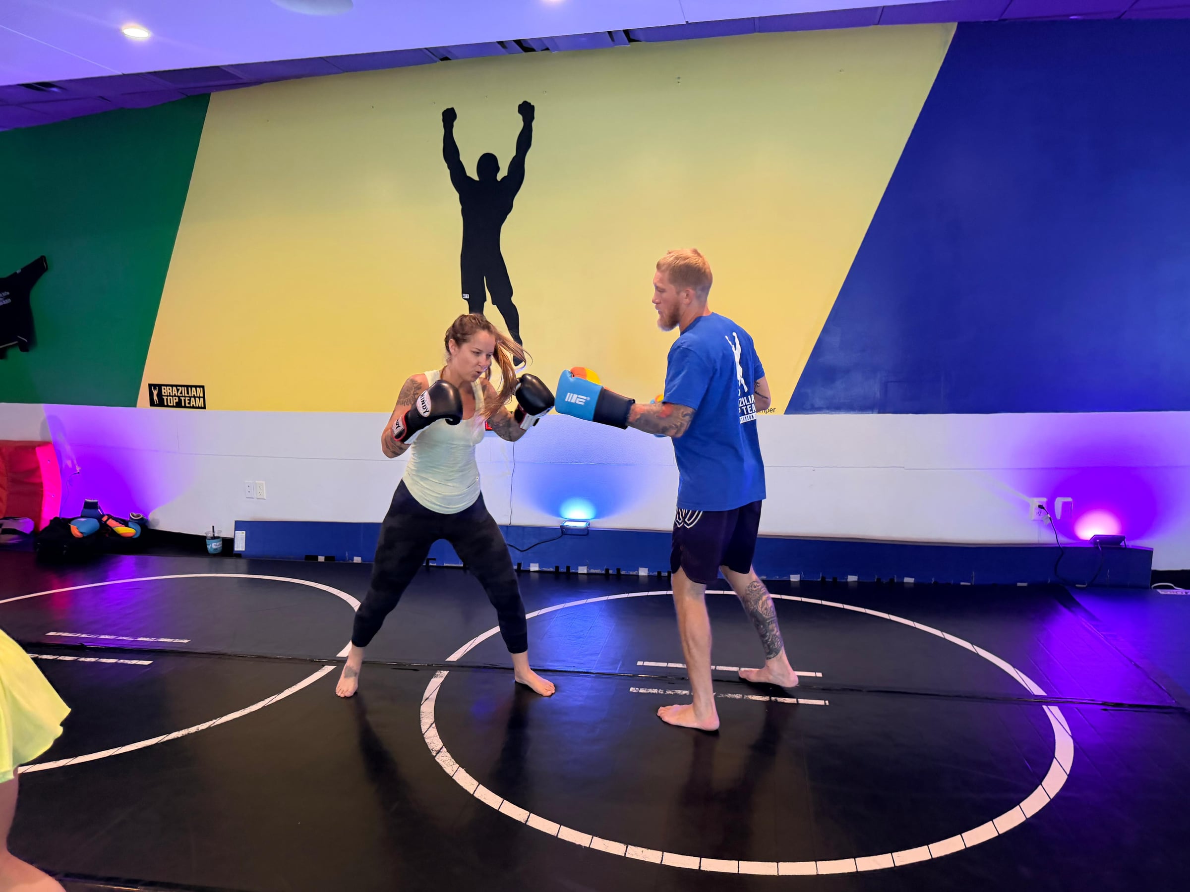 A coach holding pads for a student during the women's class